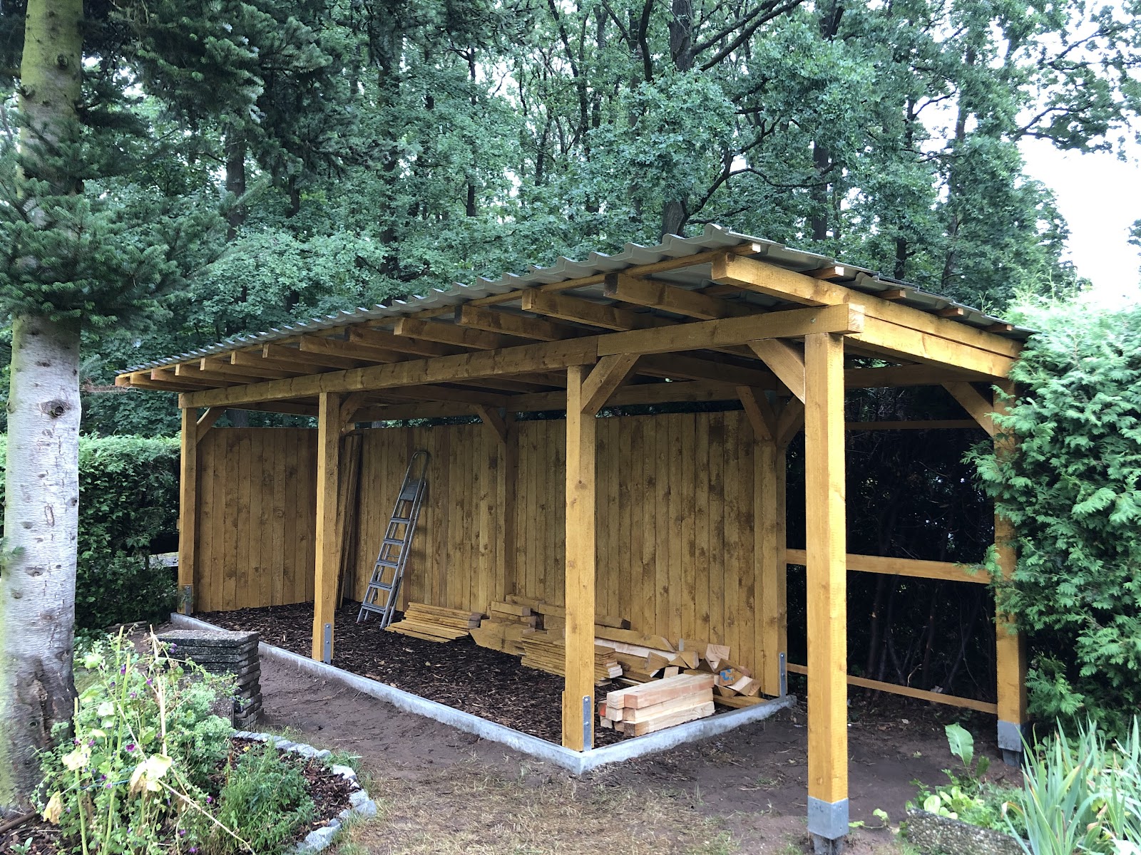 Selbst gebauter Holzunterstand mit gestapeltem Brennholz