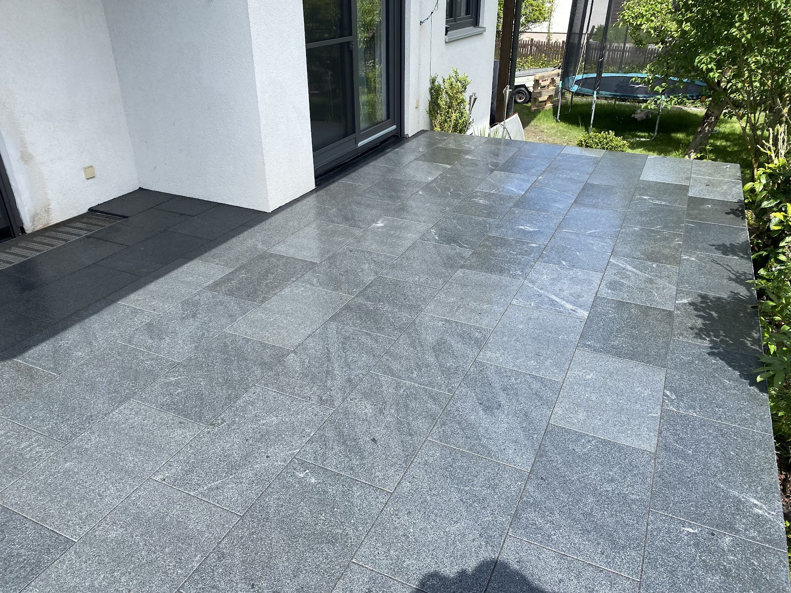 Terrasse aus grossformatigen grauen Natursteinplatten an einem Neubau
